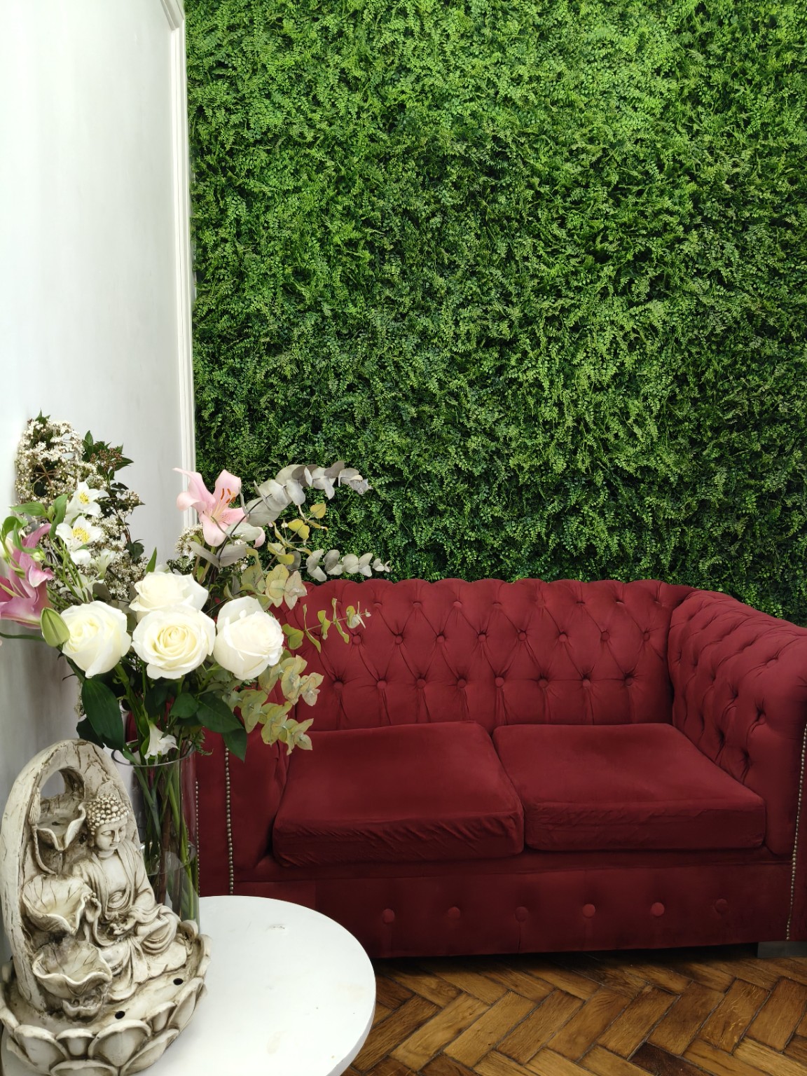Sala de espera con sillón rojo, flores y pared verde